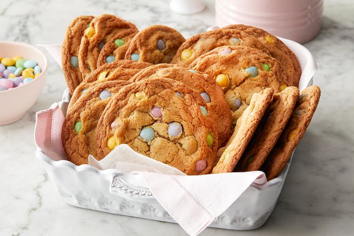 Overhead push and pulls close-up image of stacked Easter Chocolate Chip Cookies highlighting the soft centers and pastel chocolate candies embedded throughout the golden cookie surface.