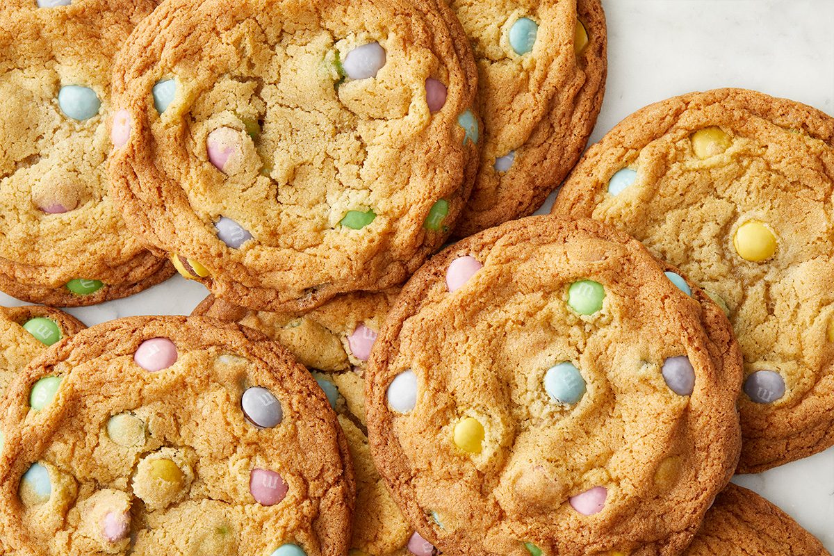 Overhead push and pulls image showcasing a tight close-up of baked Easter Chocolate Chip Cookies. The crisp edges and soft centers contrast with colorful pastel milk chocolate candies.