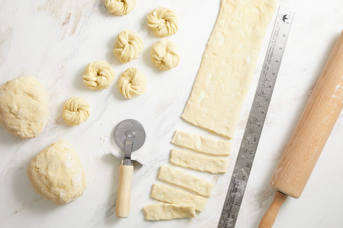 dough shaped into pastries next to strips of dough