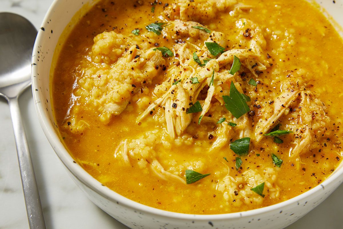 Overhead close-up of Italian Penicillin Soup with visible shredded chicken, tender pastina, and herbs. This image emphasizes texture and richness in a comforting homemade soup.