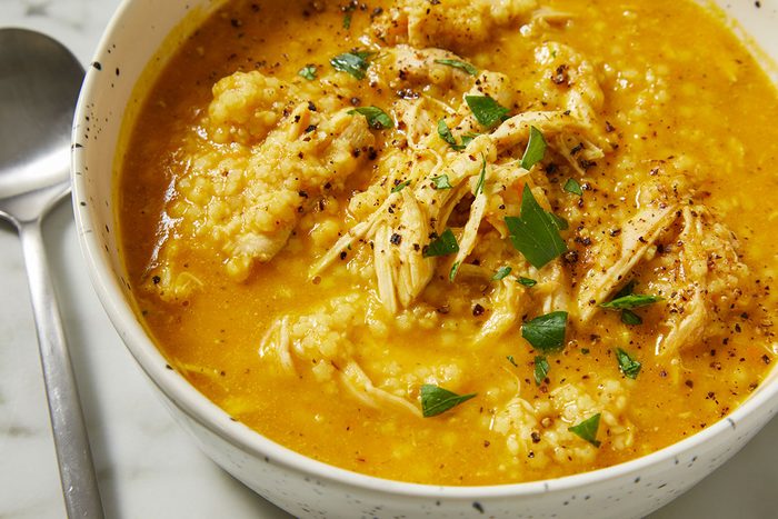 Overhead close-up of Italian Penicillin Soup with visible shredded chicken, tender pastina, and herbs. This image emphasizes texture and richness in a comforting homemade soup.