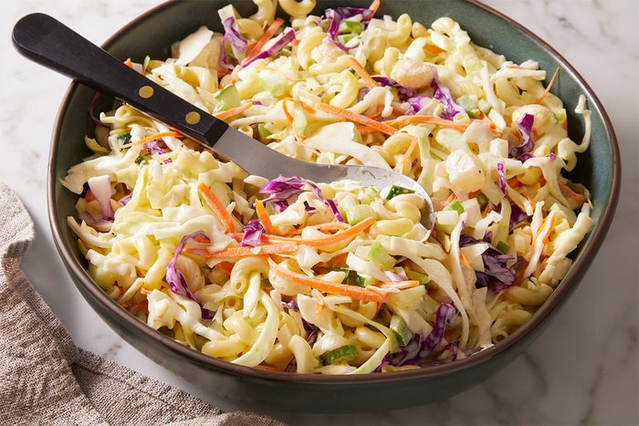 3/4th shot of Macaroni Coleslaw served in a bowl showing shredded cabbage red cabbage carrots and celery mixed with a creamy dressing