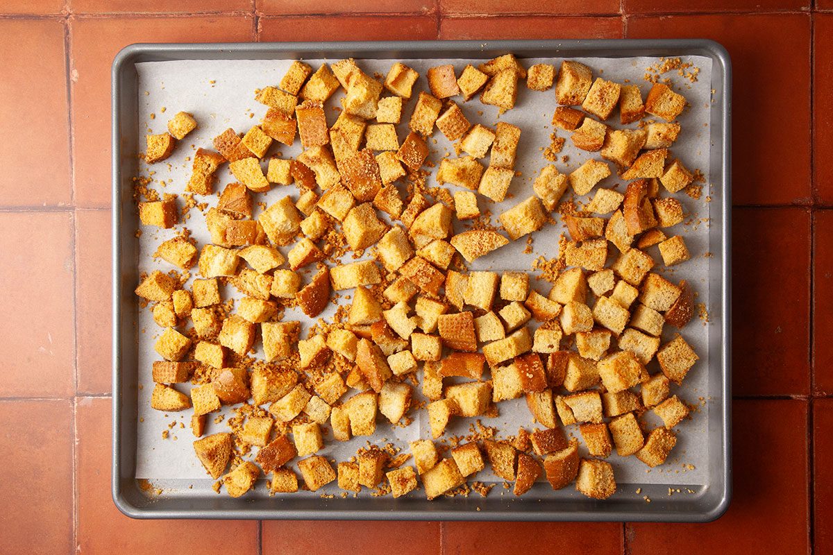 Overhead image of golden-brown croutons fresh from the oven on a sheet pan. The crisped Italian bread cubes are toasted and ready to garnish Marry Me Chicken Soup.