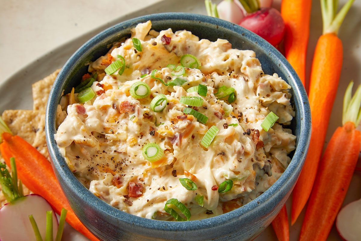 Million-Dollar Dip featuring a creamy blend of cheeses, bacon and almonds garnished with fresh green onions.