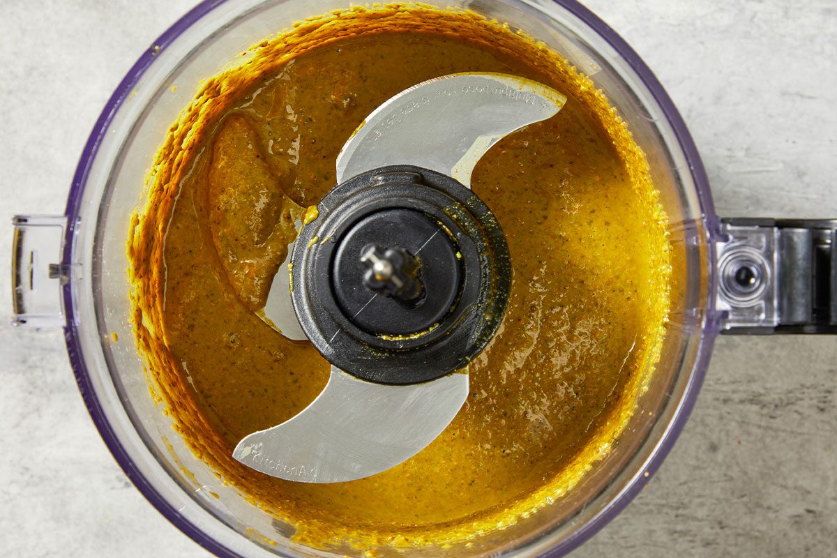 Overhead close view inside the food processor showing pistachios blended into a thick, creamy butter. The vibrant green mixture demonstrates the smooth consistency achieved after processing.