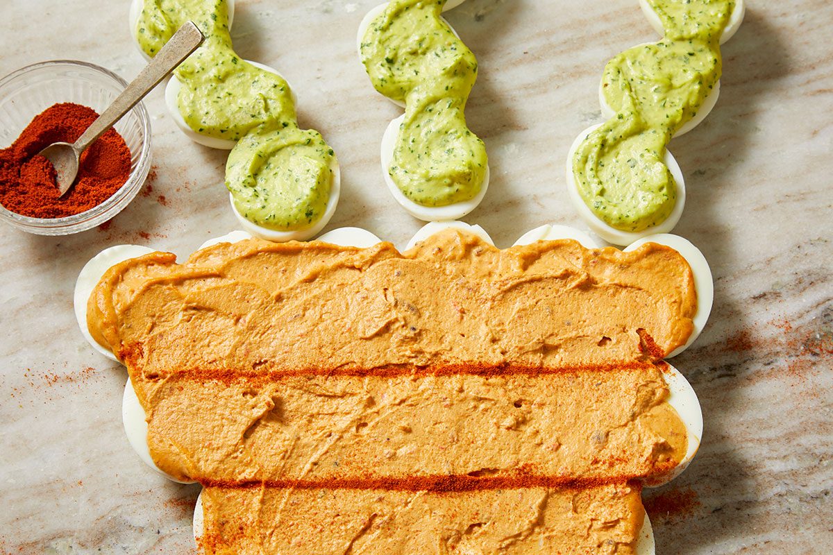 Overhead image of the fully assembled pull-apart deviled egg Easter carrot, with textured filling and green accents arranged on a rustic wooden surface.