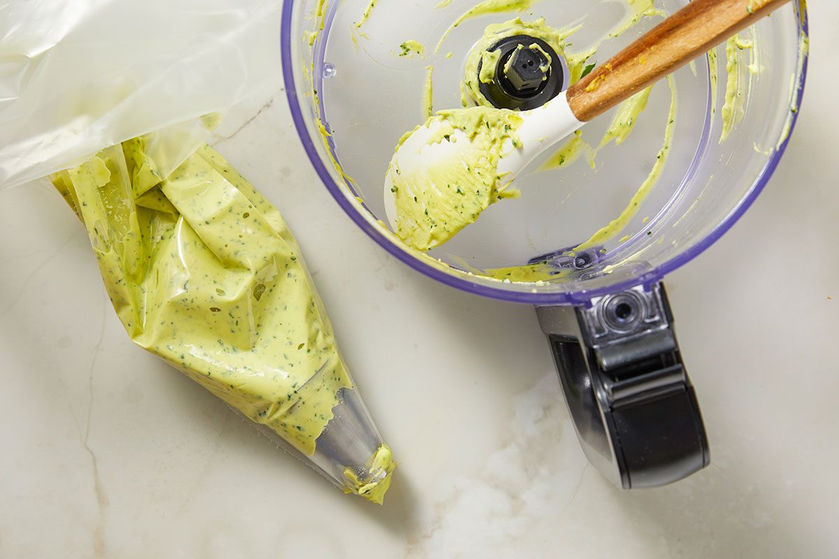 Overhead view of an empty food processor bowl with remnants of deviled egg filling, indicating completion of the blending step during recipe preparation.