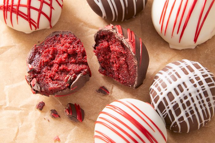 A overhead, horizontal close up shot of Red Velvet Cake bites—One appears to be broken in half displaying the caje center.
