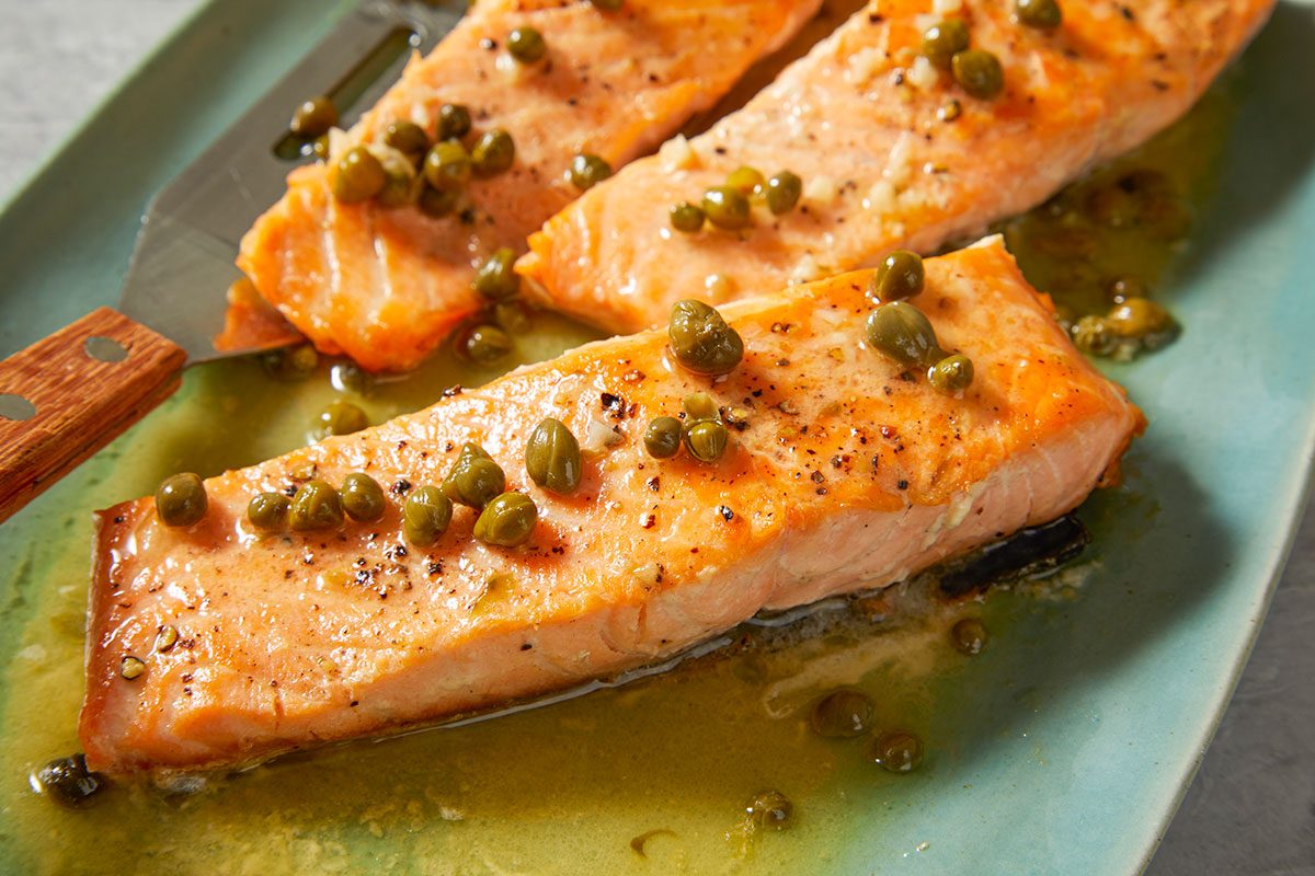 Overhead Push and Pulls image featuring a close-up of salmon fillets coated in glossy lemon caper butter sauce, highlighting texture and color.