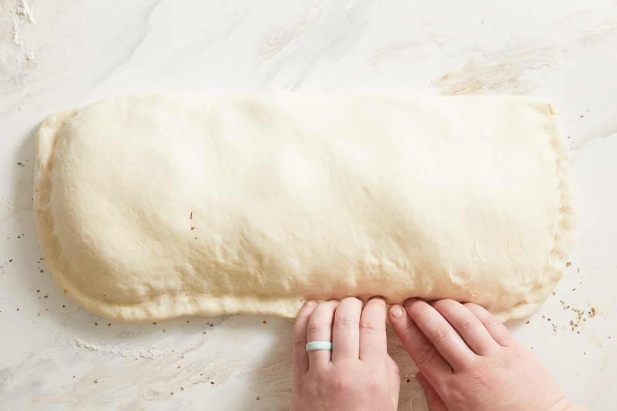sealing the edges of the dough by pinching and folding